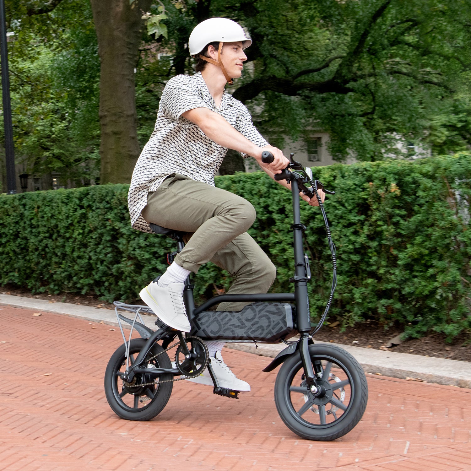 person riding j5 bike down the street in a helmet