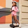 young girl standing on amber kick scooter