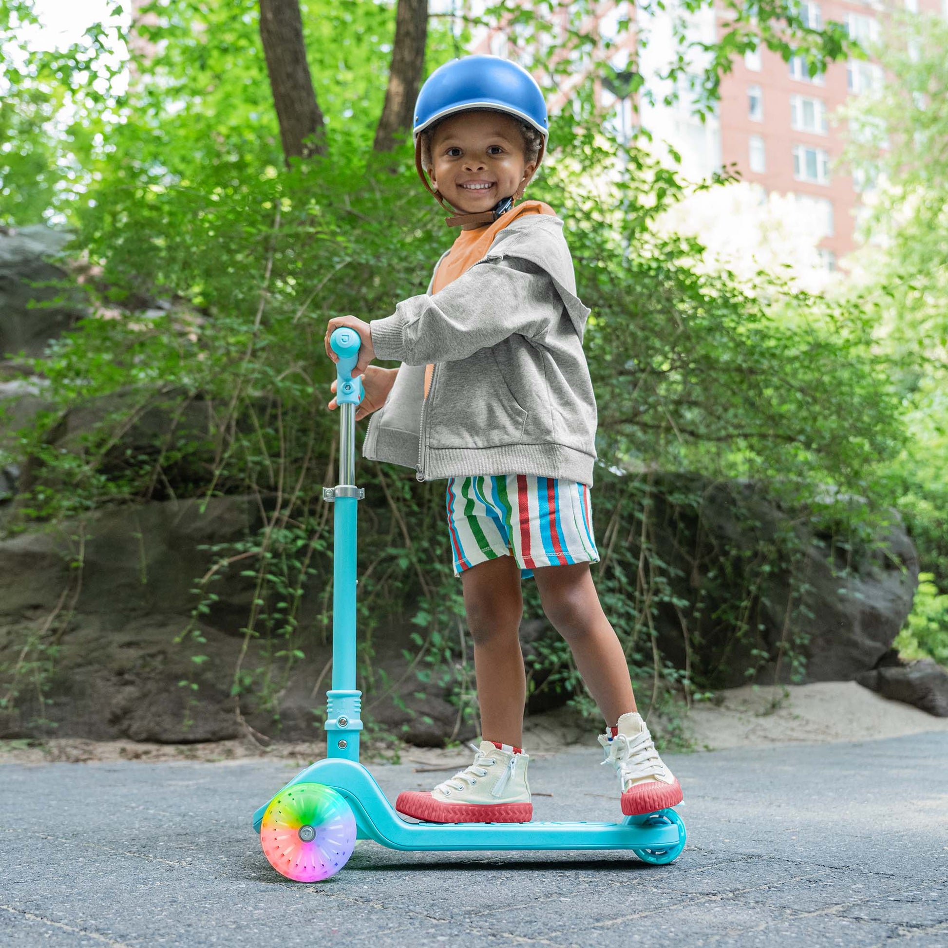 kid riding blue bloom kick scooter in the park