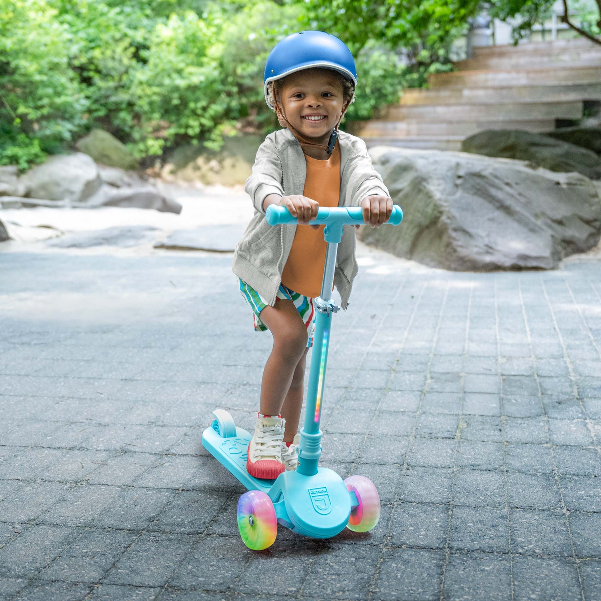kid riding the blue bloom kick scooter through the park