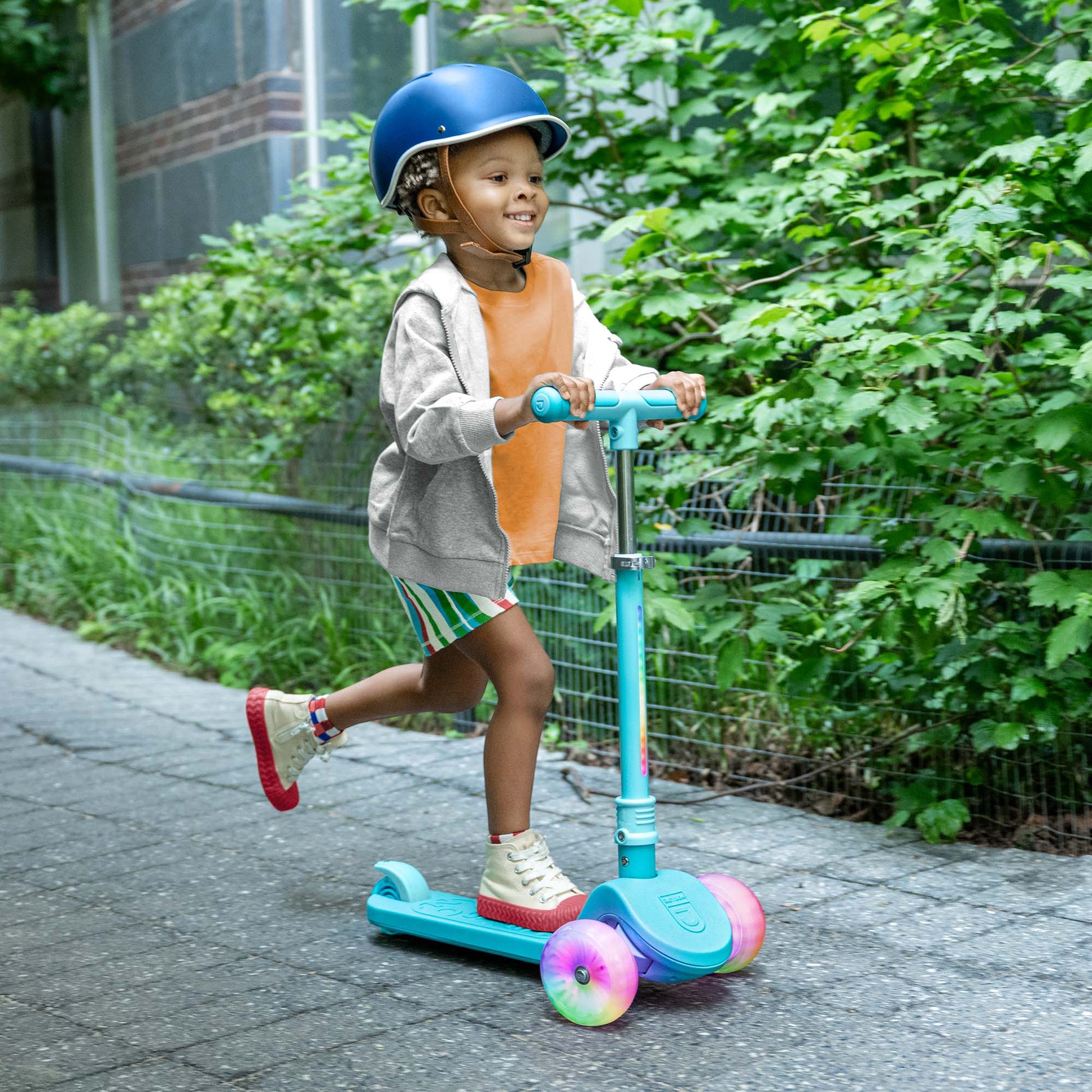 kid riding blue bloom kick scooter with a helmet on