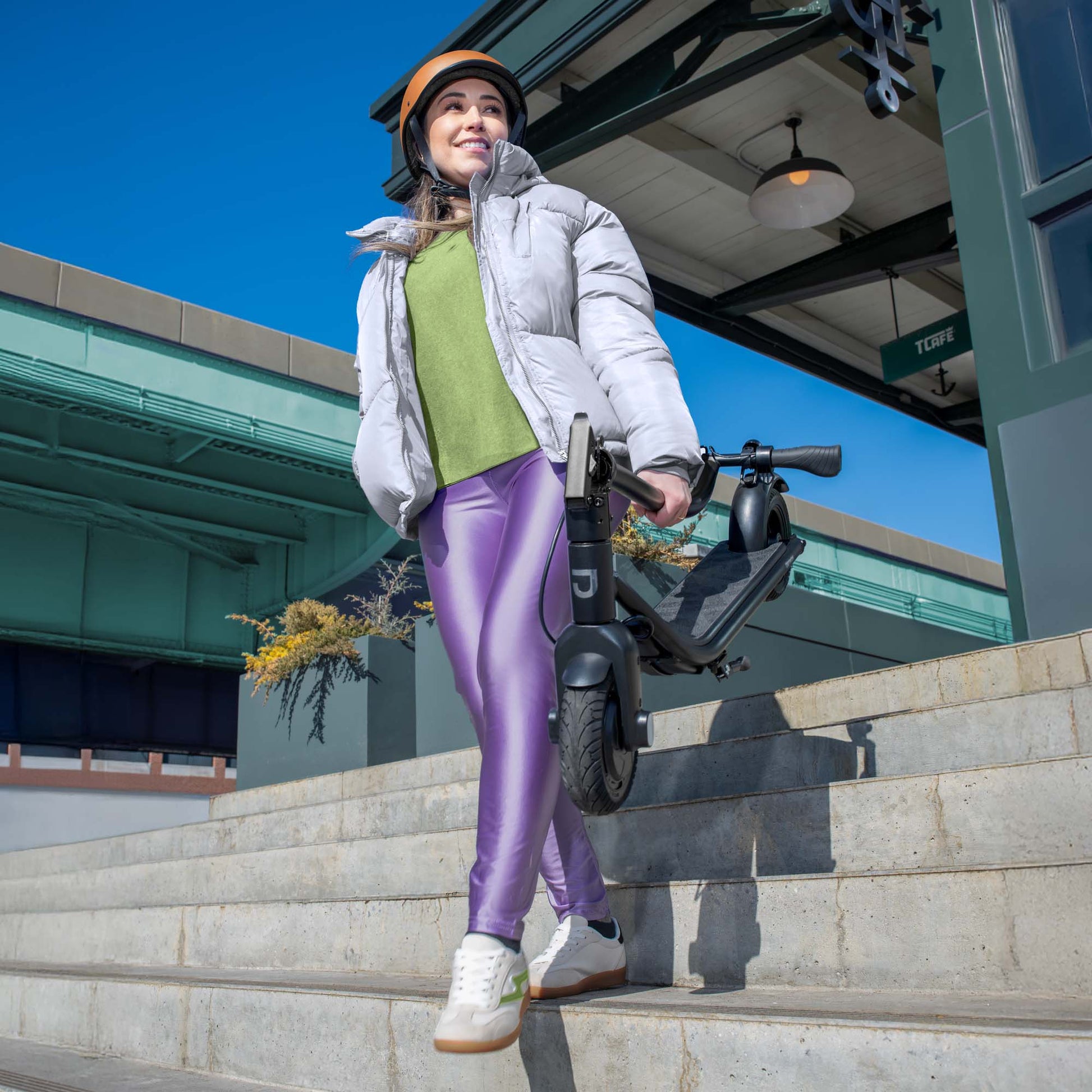 person carrying folded ember e-scooter down the stairs