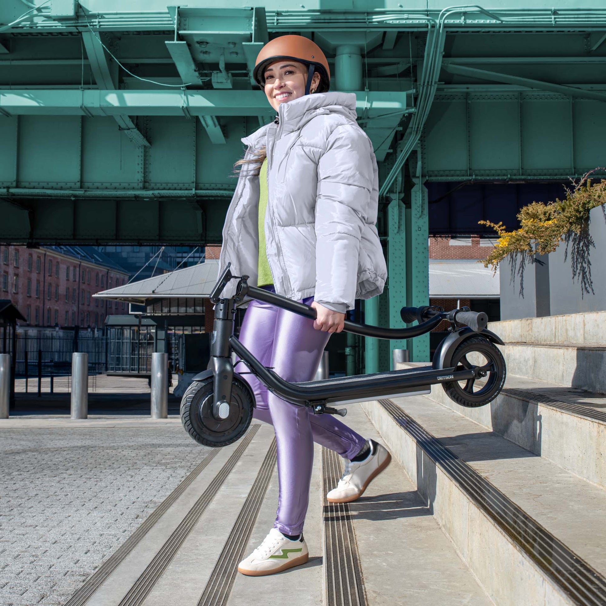 person carrying folded ember e-scooter down the stairs