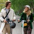 two people walking side by side while holding their white and black eris scooters