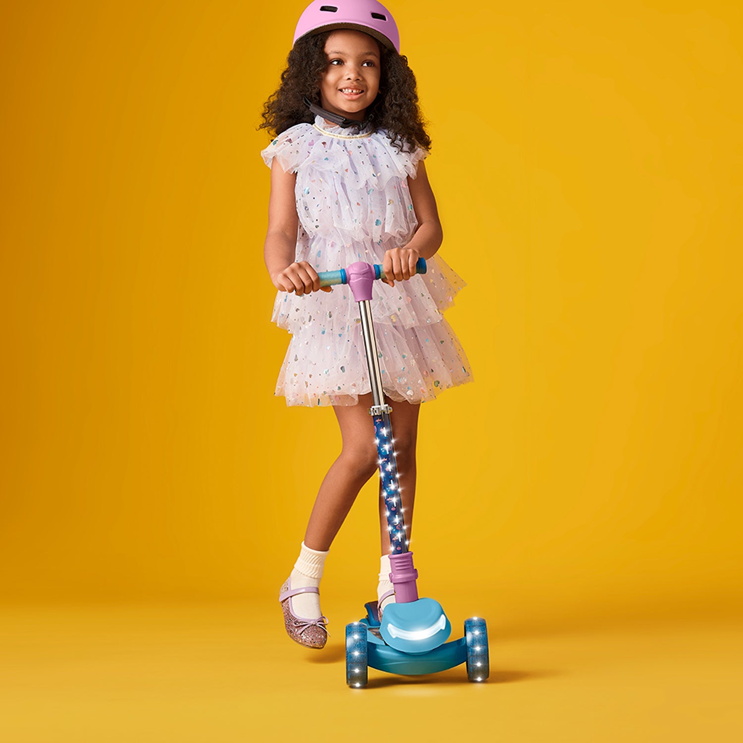 young girl in a helmet standing on frozen kick scooter
