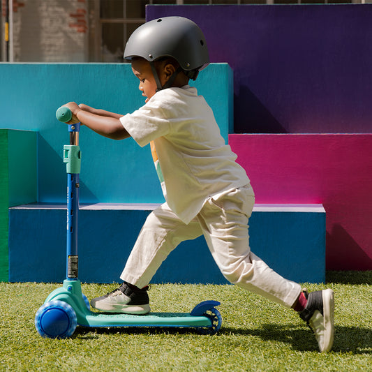 young kid riding gem kick scooter on grass