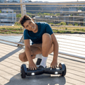 kid resting hands on footpads of black spin hoverboard