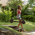 woman walking down side walk holding foldable Eris scooter