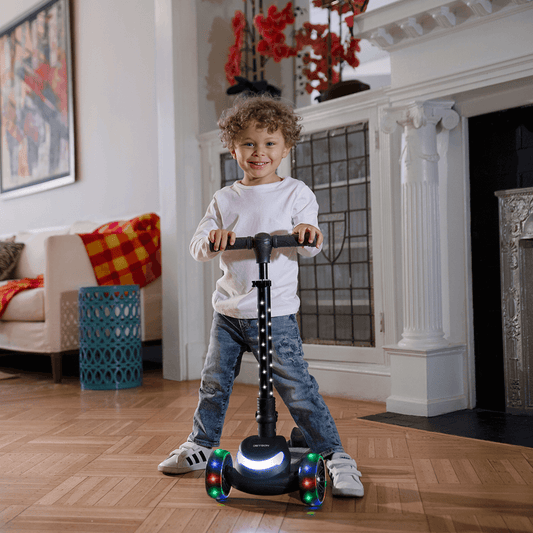 young kid holding onto jupiter mini kick scooter in the living room