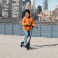 kid riding black jupiter jumbo scooter along the waterfront