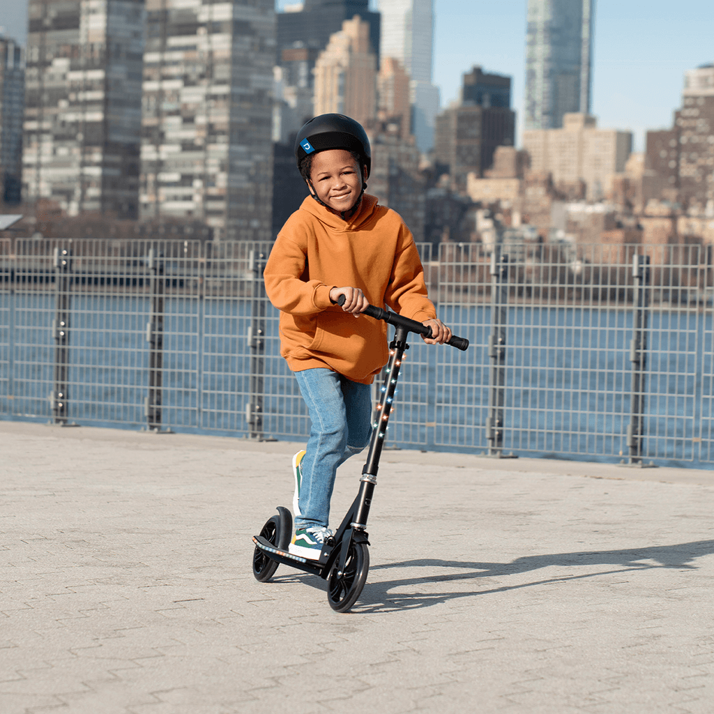 kid riding black jupiter jumbo scooter along the waterfront