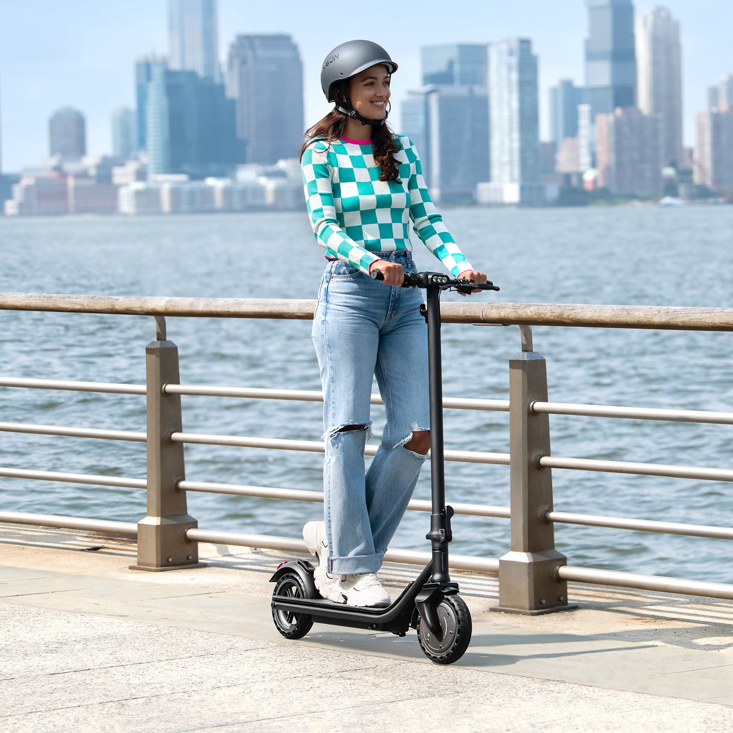 person riding the Racer e-scooter with a city landscape in the  background along with a river