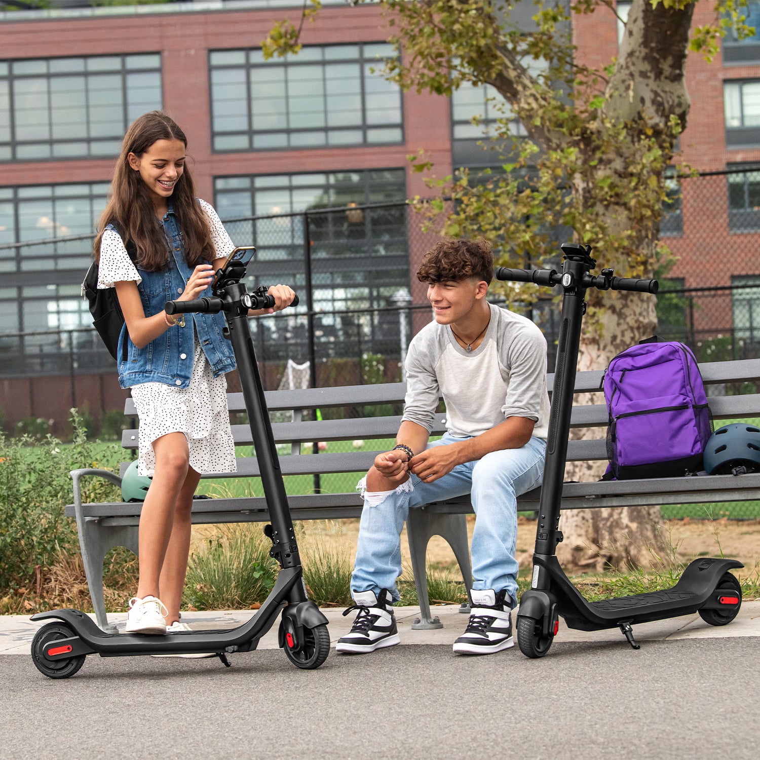 two people stopped with the Rhythm e-scooter one person is on a bench and the other is messing with their phone that is in the phone holder of the Rhythm