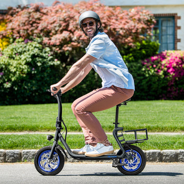 A man riding a scooter and smiling at the camera.