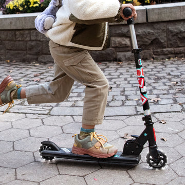 young kid riding a two wheel kick scooter
