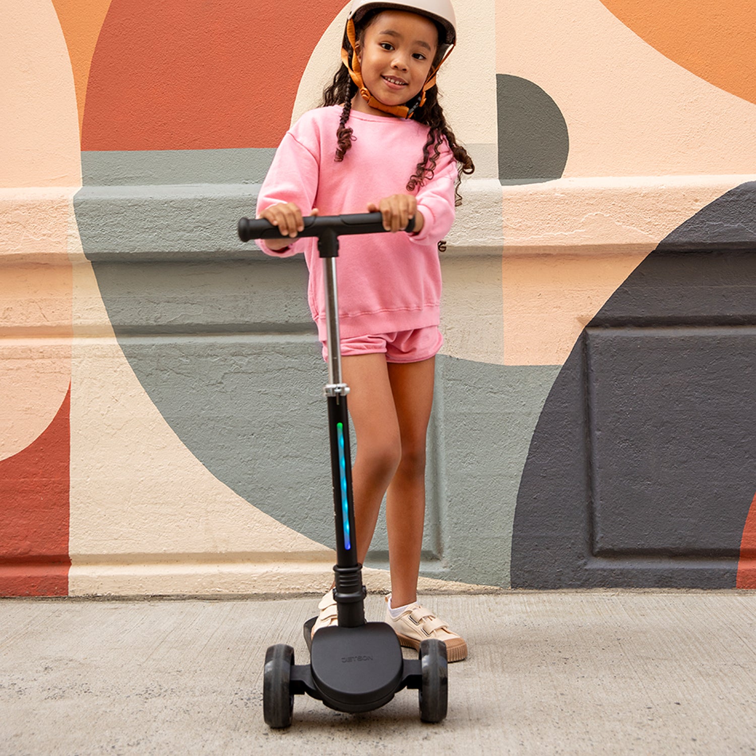 young girl standing on amber kick scooter facing forward