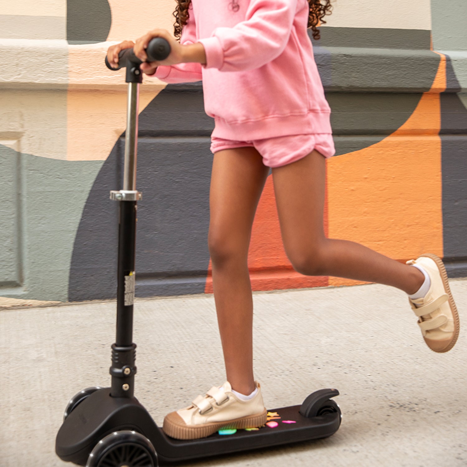 young kid riding amber kick scooter on the sidewalk