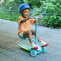 kid wearing a helmet riding the aria kick scooter using the seat