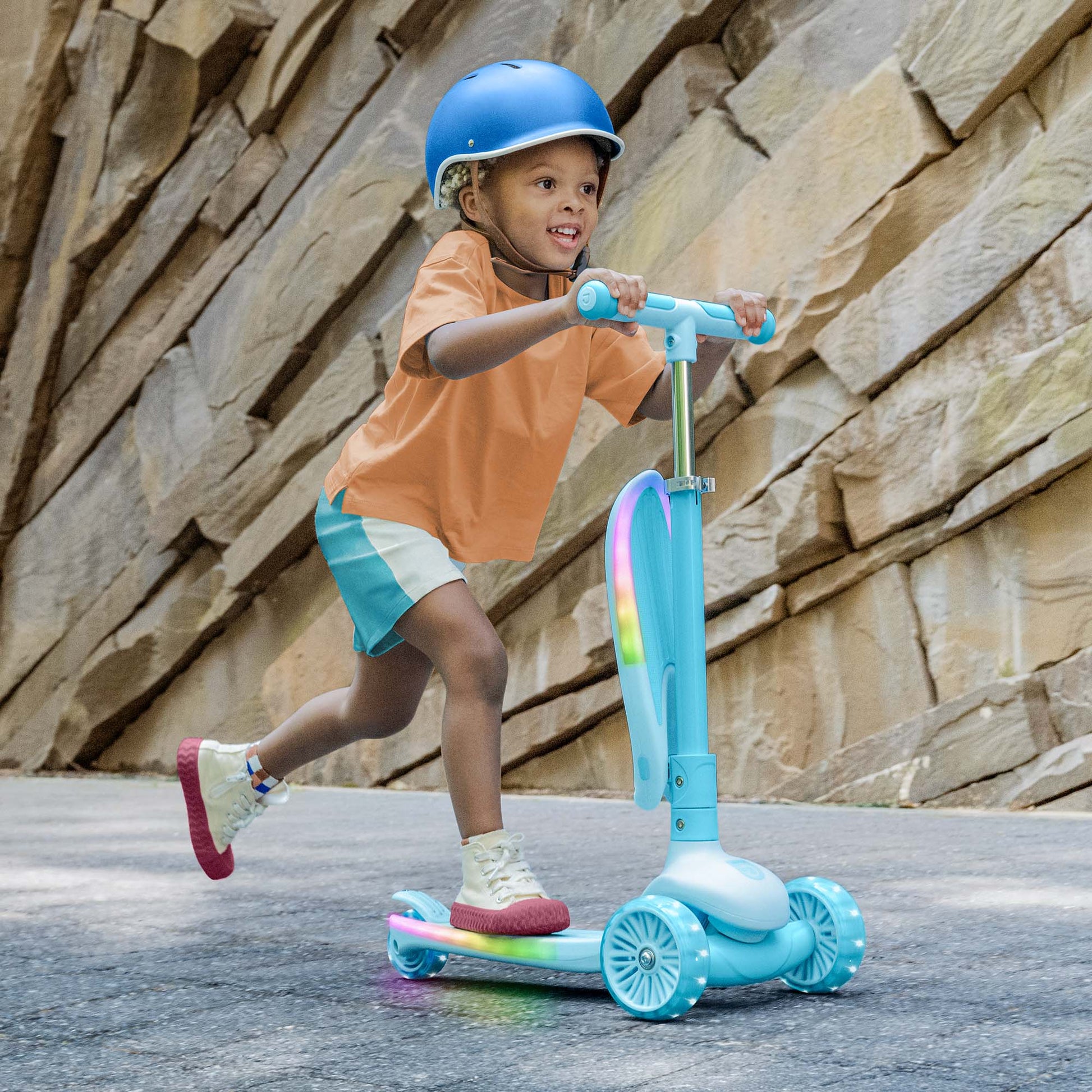 kid in a helmet riding the aria kick scooter