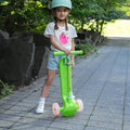 little kid holding a folded green bloom kick scooter