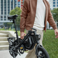 person carrying folded bolt pro x electric bike by carrying handle