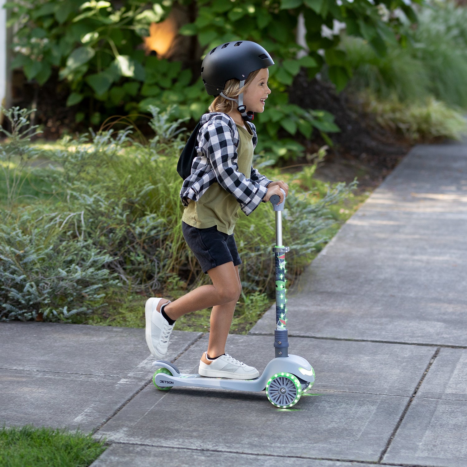 young kid riding the disney grogu kick scooter on the sidewalk