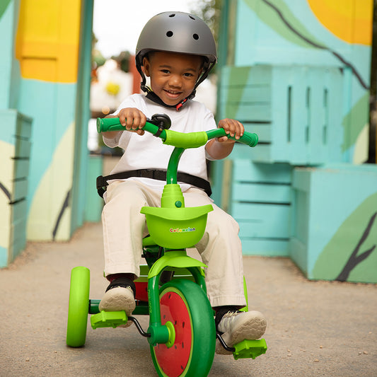 young child in a helmet pedaling on the cocomelon light up trike