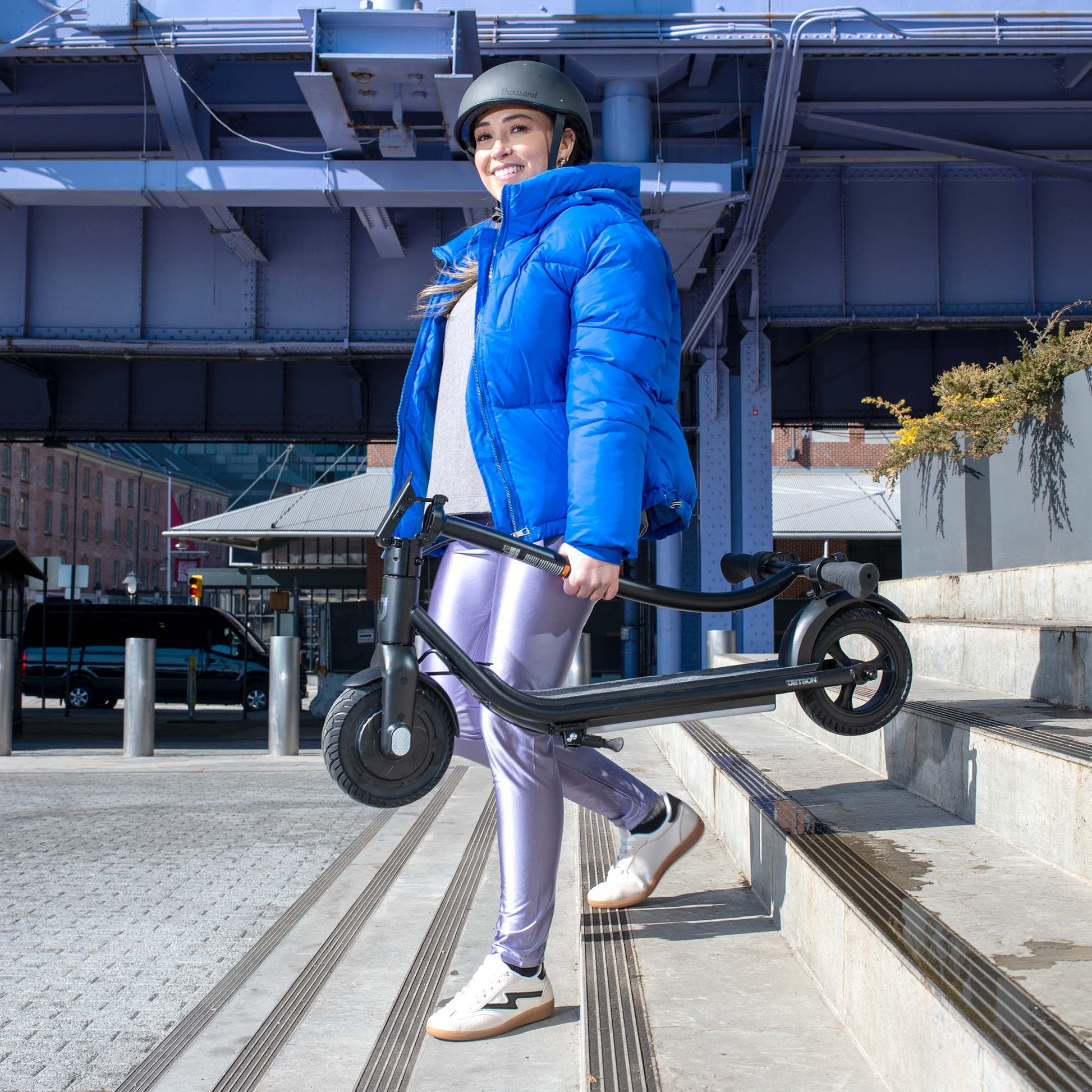 person carrying folded ember electric scooter down steps