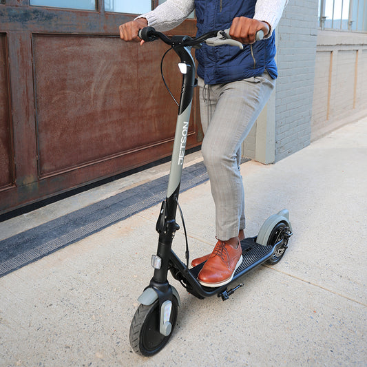 person holding onto handlebars and standing on eris pro electric scooter