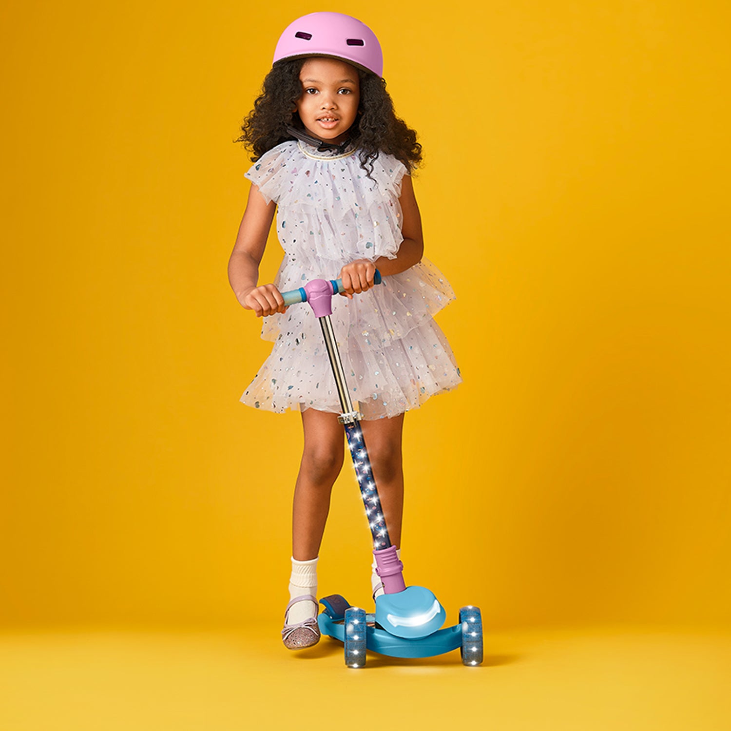 young girl in a helmet standing on frozen kick scooter