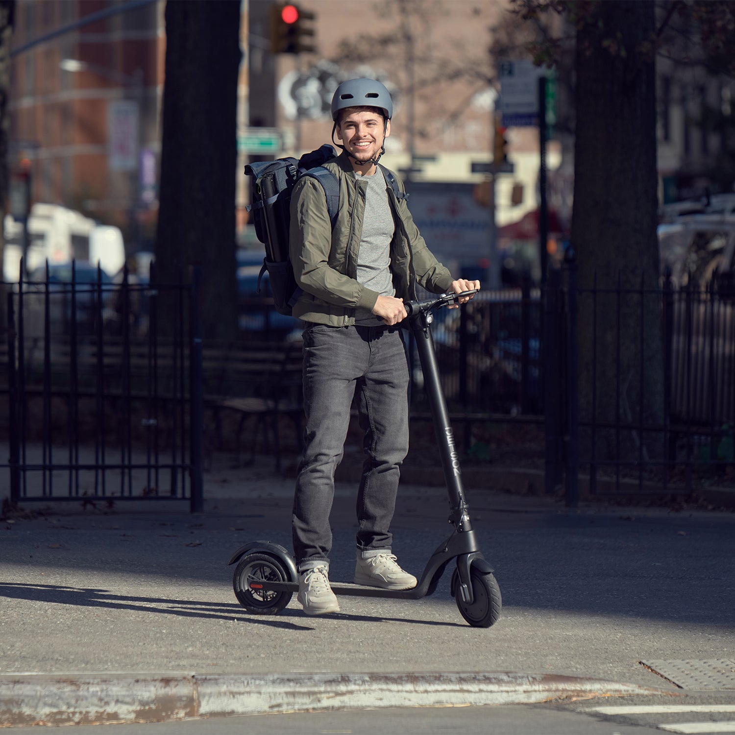 man standing with the knight scooter on the sidewalk
