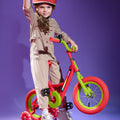 young kid sitting on red and green kids bike