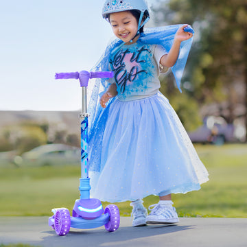 little girl standing next to her Frozen 3 wheel kick scooter