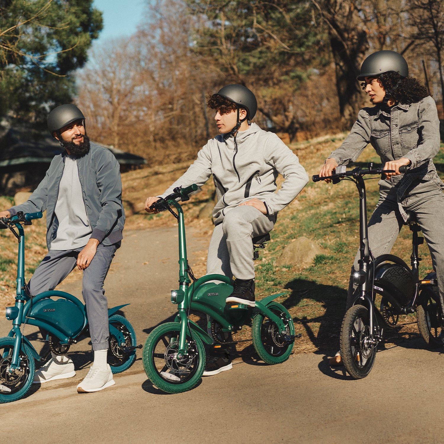 three people with helmets sitting on Bolt Pro bikes in a park