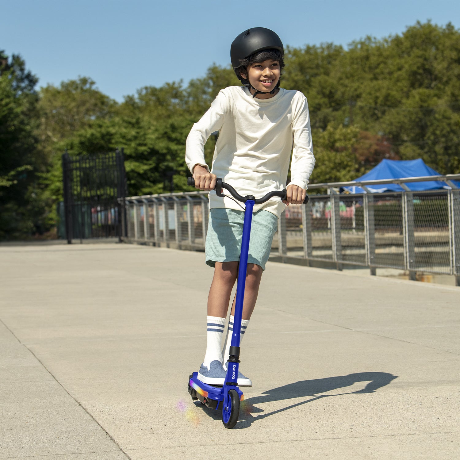 Boy riding the blue echo x electric scooter through a playground