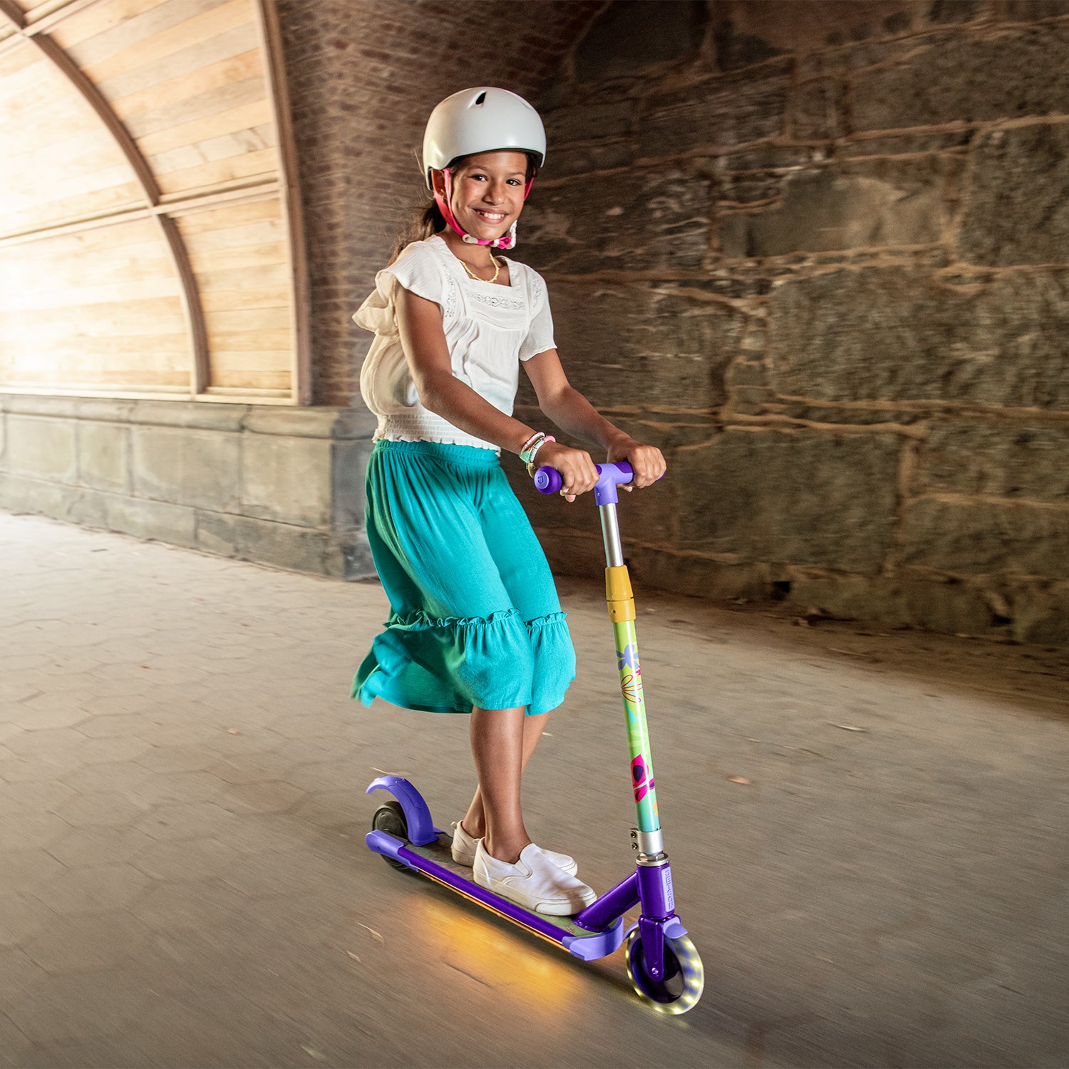 young girl riding the disney encanto electric scooter through a tunnel