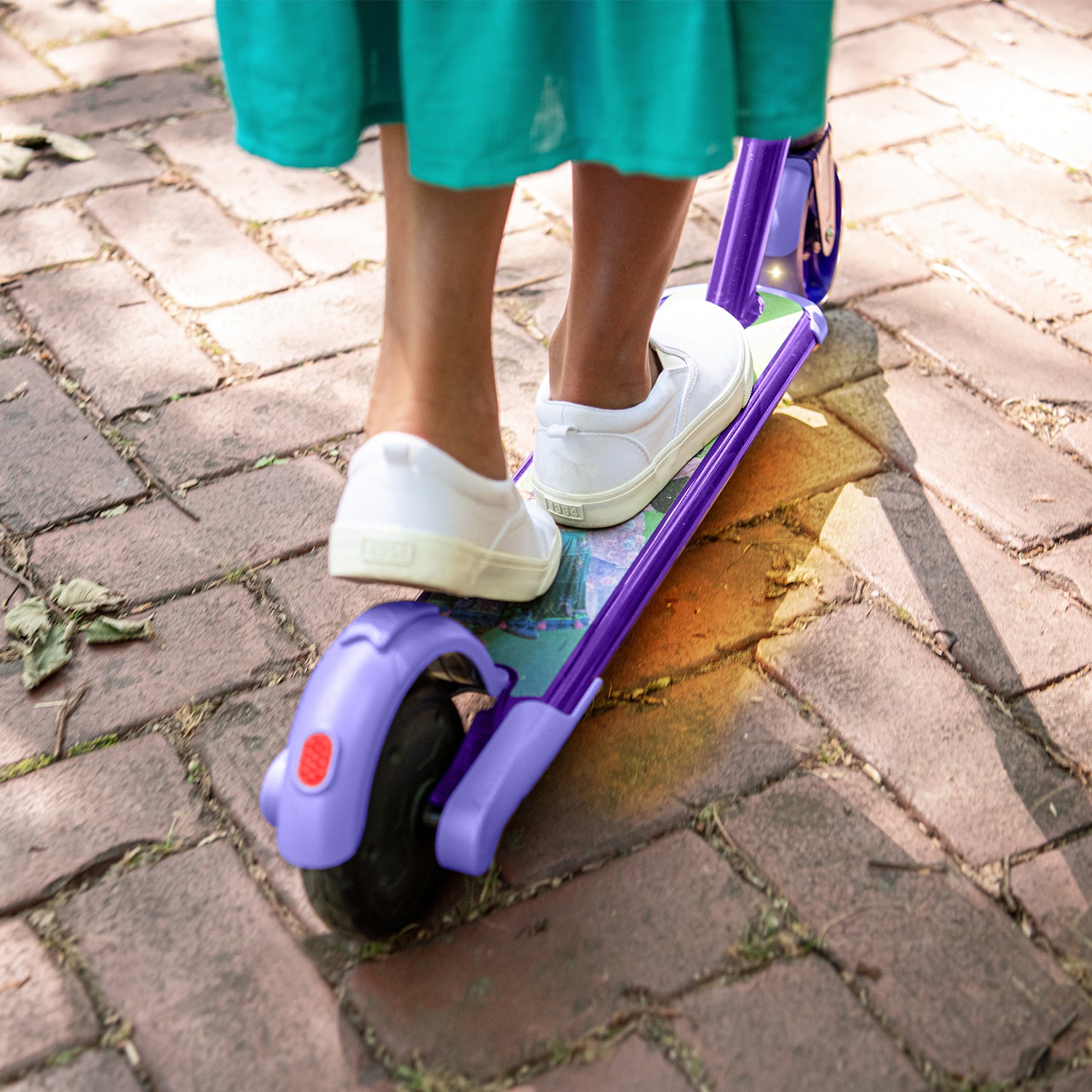 close up of a child's feet on the deck of the disney encanto electric scooter