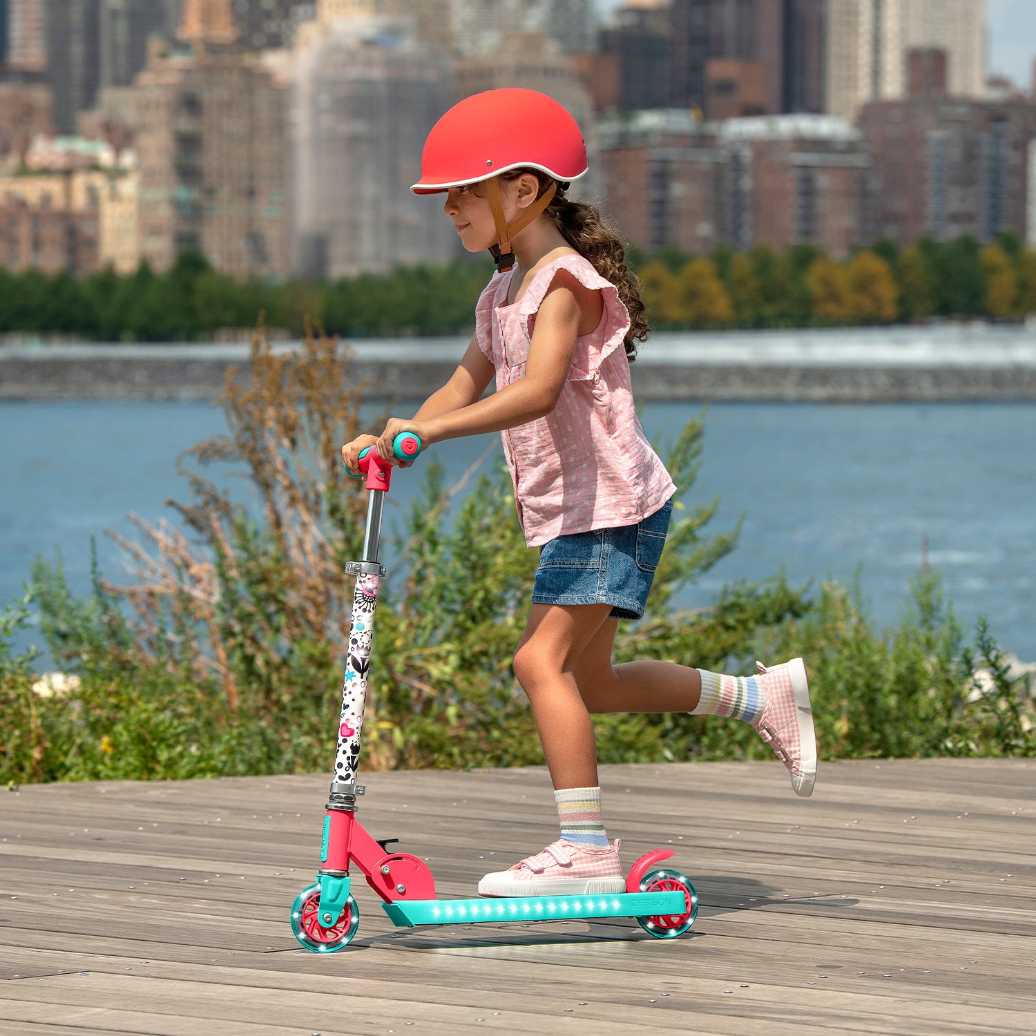 young girl riding the gabby's dollhouse kick scooter along the boardwalk