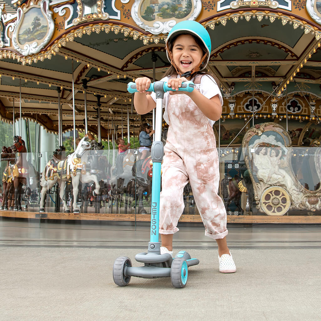 young kid holding onto the handlebar on the blue gleam kick scooter 