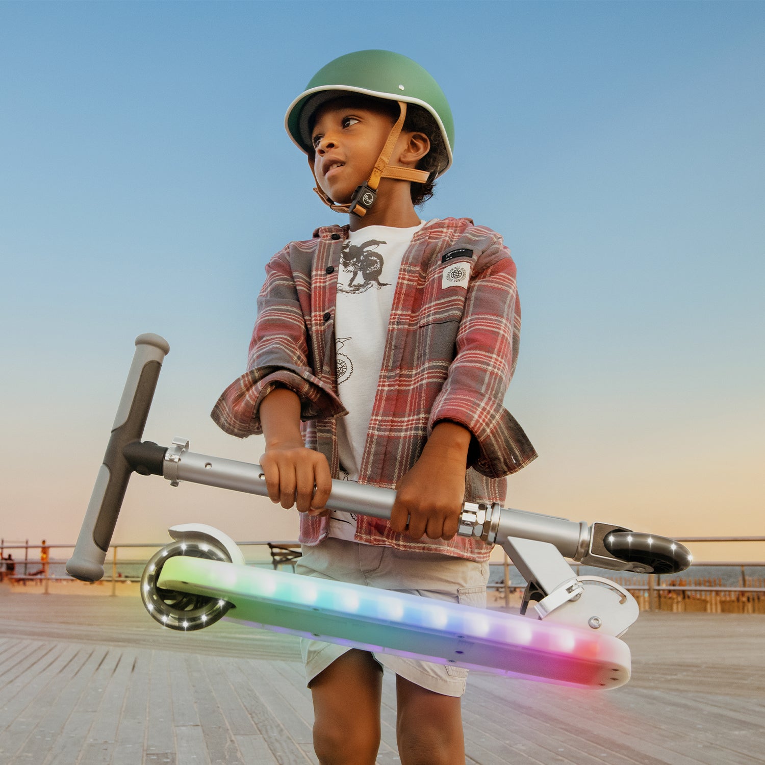 kid holding a folded silver helio x kick scooter