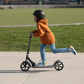 kid riding black jupiter jumbo scooter through a park
