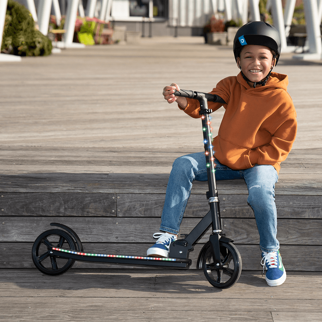 kid sitting down on a step and holding onto black jupiter jumbo scooter
