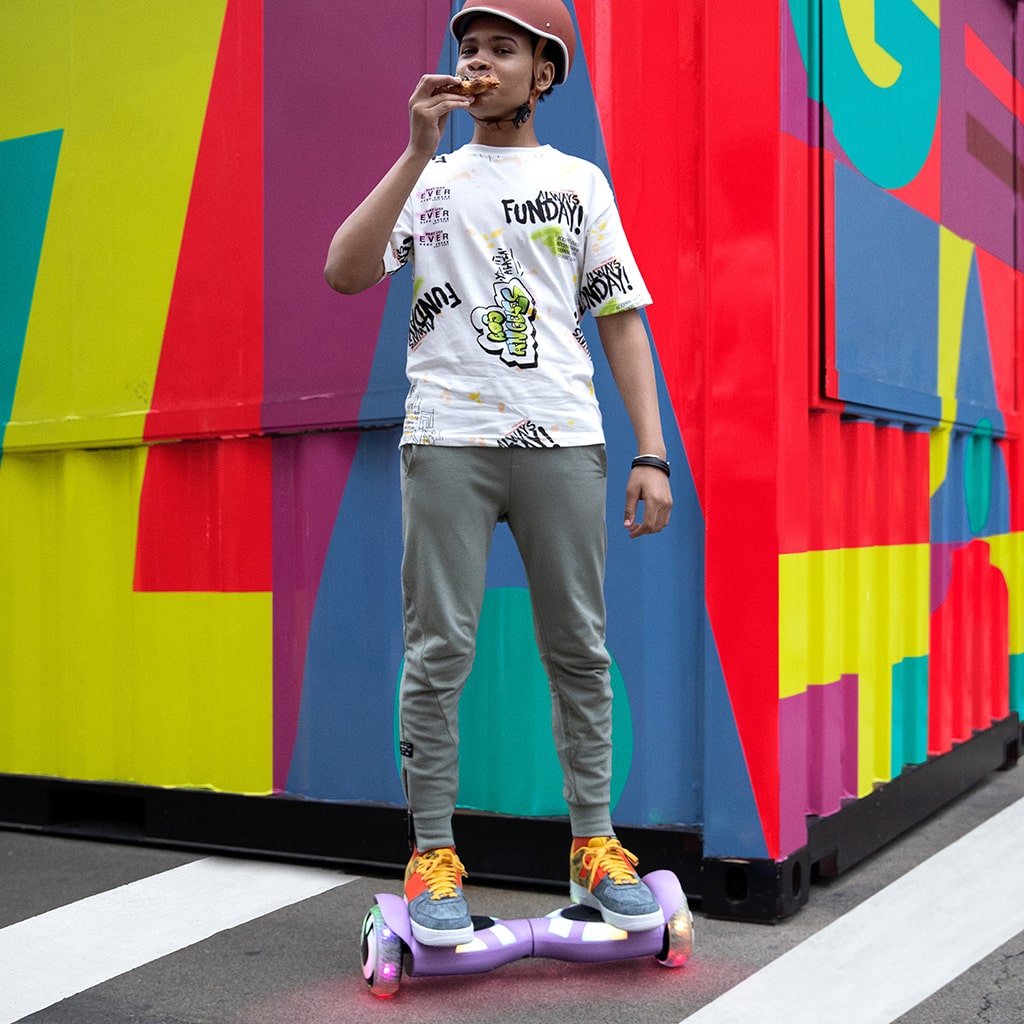 young boy eating and riding the Litho X hoverboard