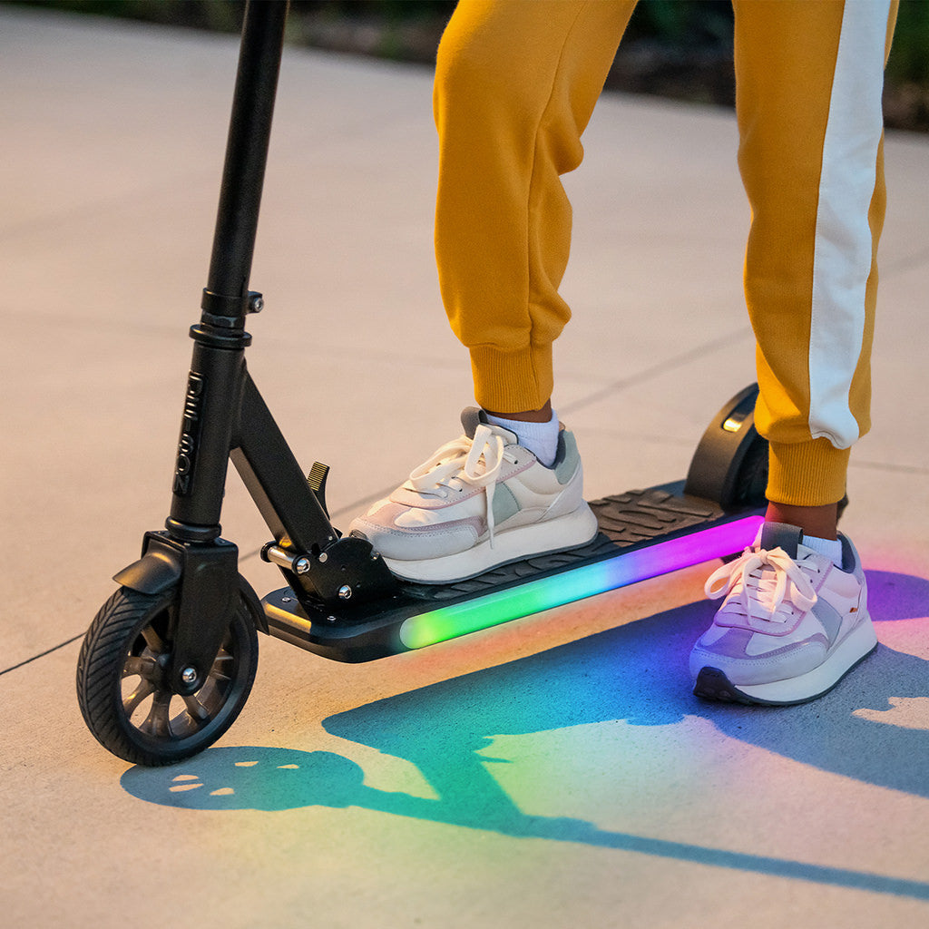 girl at a stand still with one foot on e-scooter and another on the ground