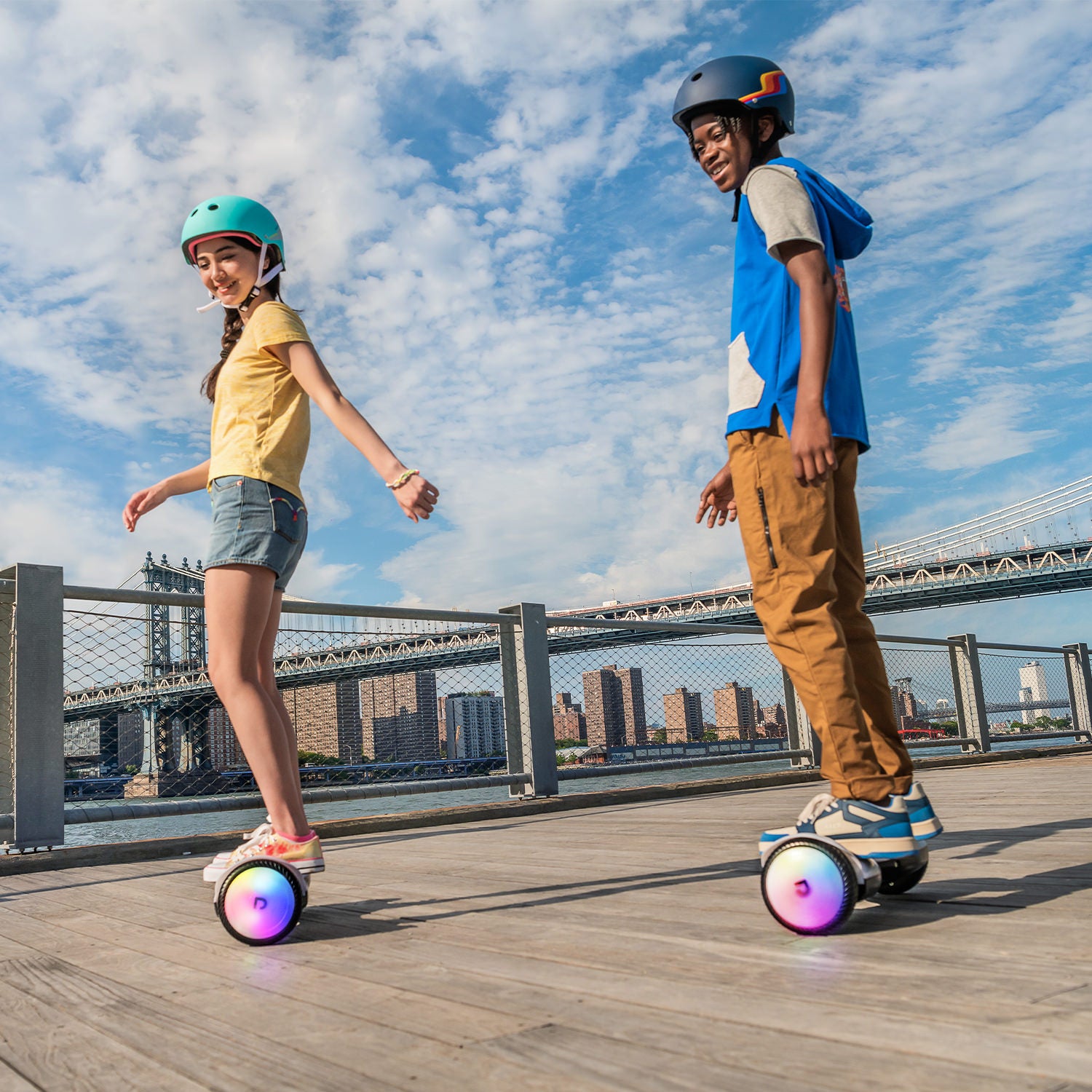 two kids riding their Plasma X hoverboards on a pier next to the water