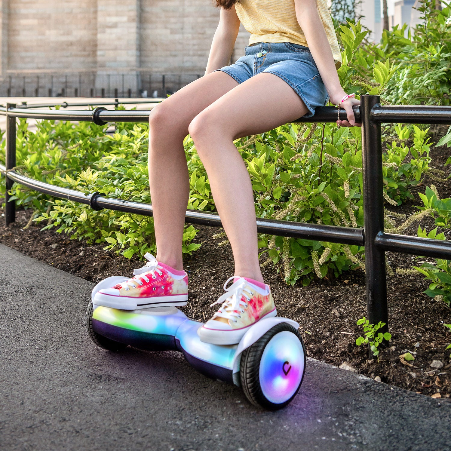 person sitting on a railing while resting their feet on the top of the Plasma X hoverboard