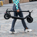 side view of a person holding and carrying a folded Racer e-scooter