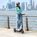 person riding the Racer e-scooter with a city landscape in the  background along with a river 