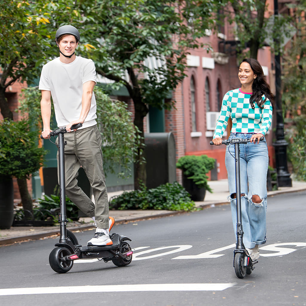 two people riding down the street on their e-scooters 