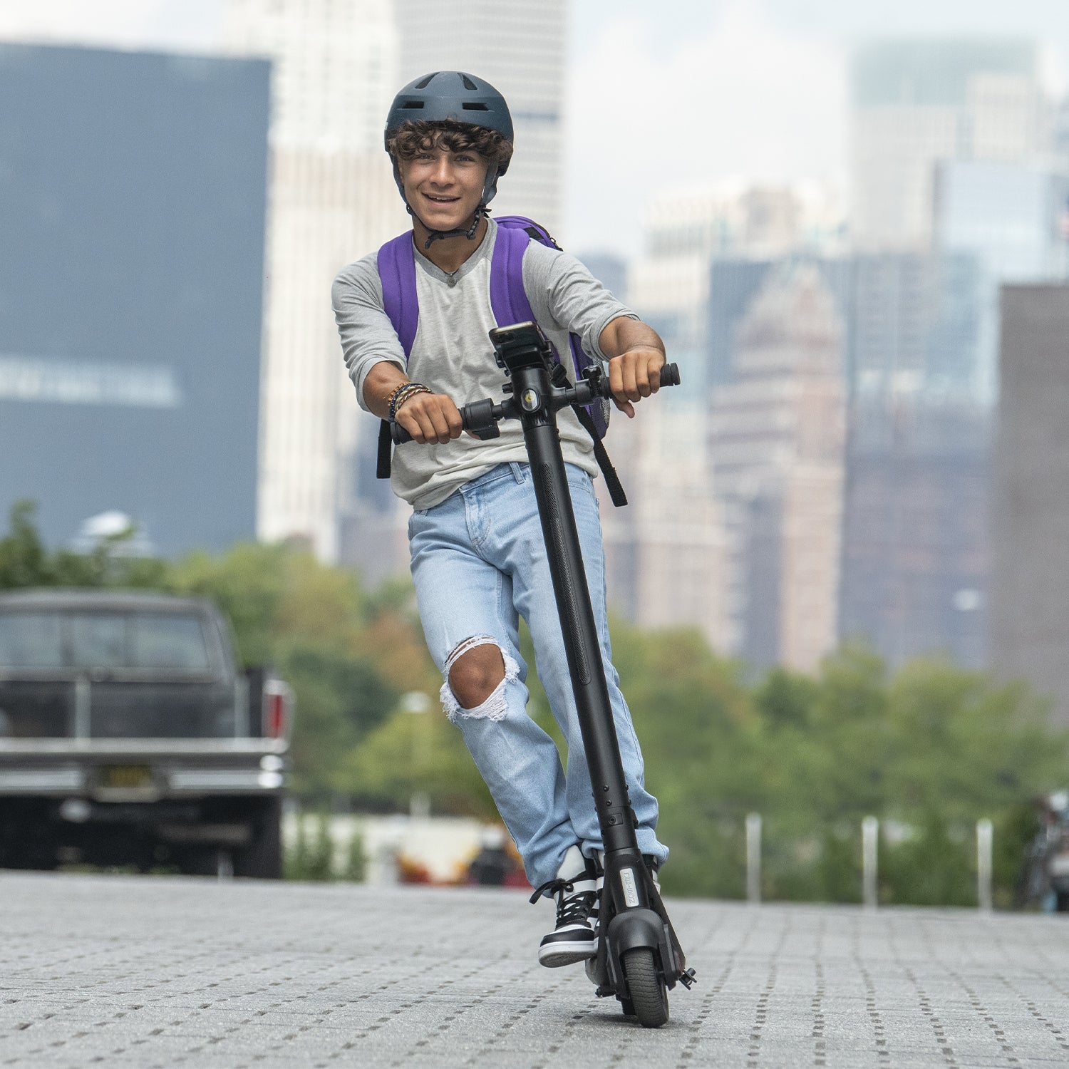 young person riding on the Rhythm e-scooter outside and they are leaning to steer 